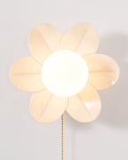 Front view of the lit flower wall light from Clérachic, with a six-petal rim in warm cream and a large frosted globe.