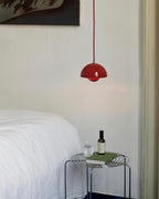 Clérachic's Flowerpot pendant in red, its cord dropping straight down beside a neatly made bed.