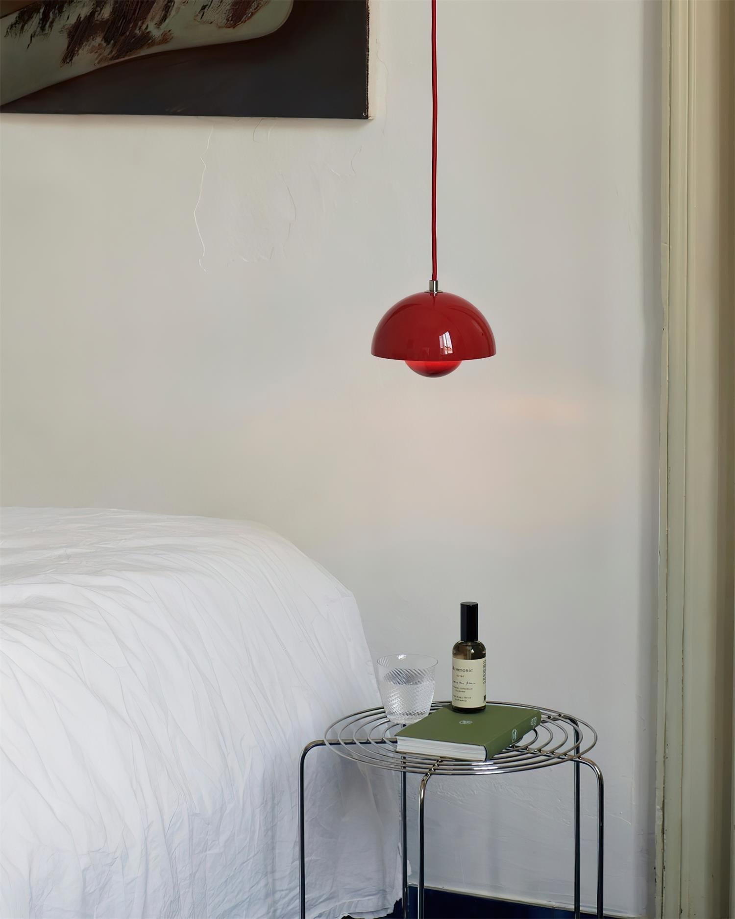 Clérachic's Flowerpot pendant in red, its cord dropping straight down beside a neatly made bed.