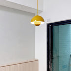 The Clérachic Flowerpot pendant in mustard yellow, hung from its plug-in cord near a bright window.