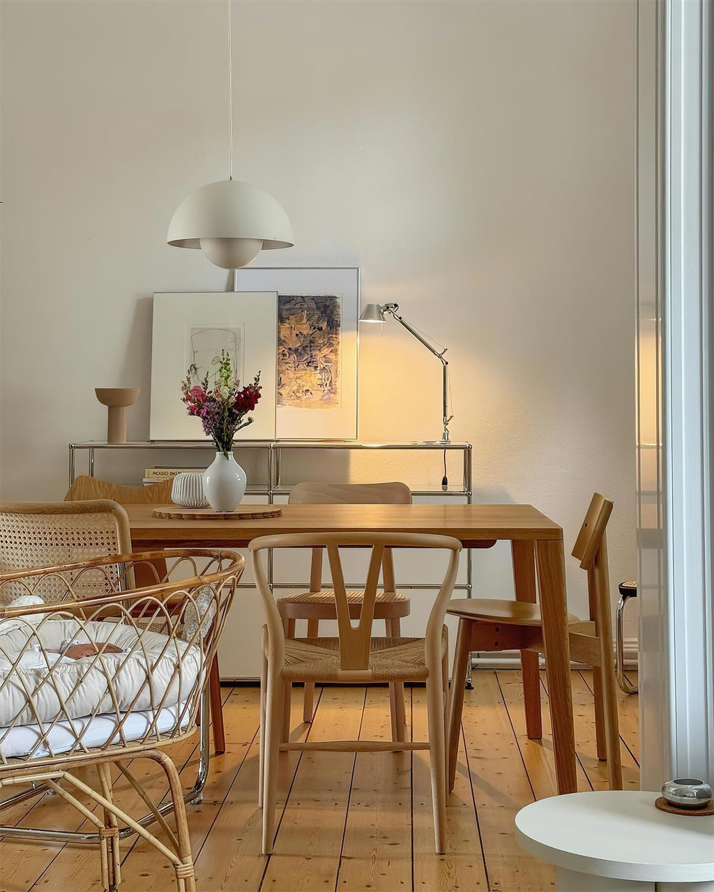 The Clérachic Flowerpot pendant in white, its cord rising to a hook above a wooden dining table.