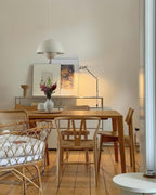 The Clérachic Flowerpot pendant in white, its cord rising to a hook above a wooden dining table.