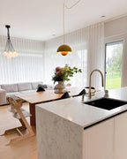 The Clérachic Flowerpot pendant in yellow, plugged in above an open dining and kitchen space.