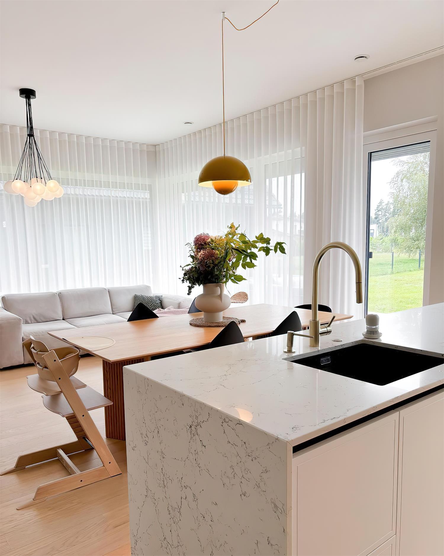The Clérachic Flowerpot pendant in yellow, plugged in above an open dining and kitchen space.