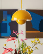 The Clérachic Flowerpot pendant in yellow, its dome shade set against a bold, colourful backdrop.