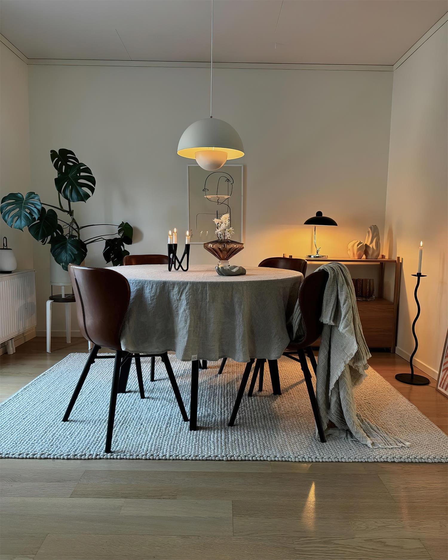 Clérachic's Flowerpot pendant in white, hung on its long cord above a round dining table.
