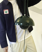 Clérachic's Flowerpot pendant in dark green, its plug-in cord and dome shade carried by hand.