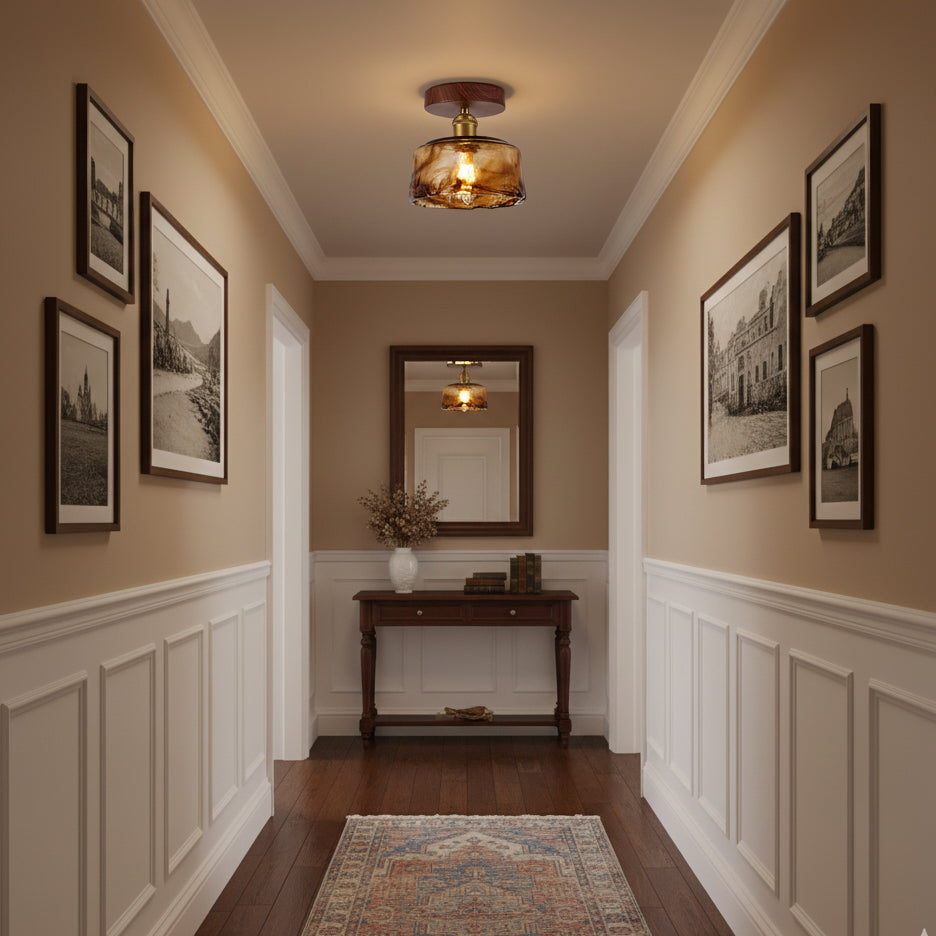 A Clérachic amber glass flush ceiling light in a panelled hallway with framed prints, a console table and a patterned runner.