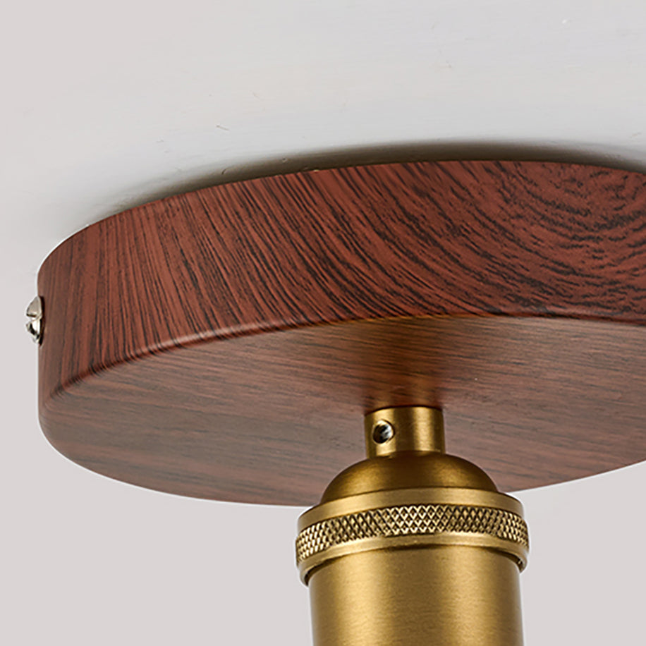 Close view of the walnut-effect canopy, brass knurled socket collar and screw fixing on this Clérachic flush ceiling light.