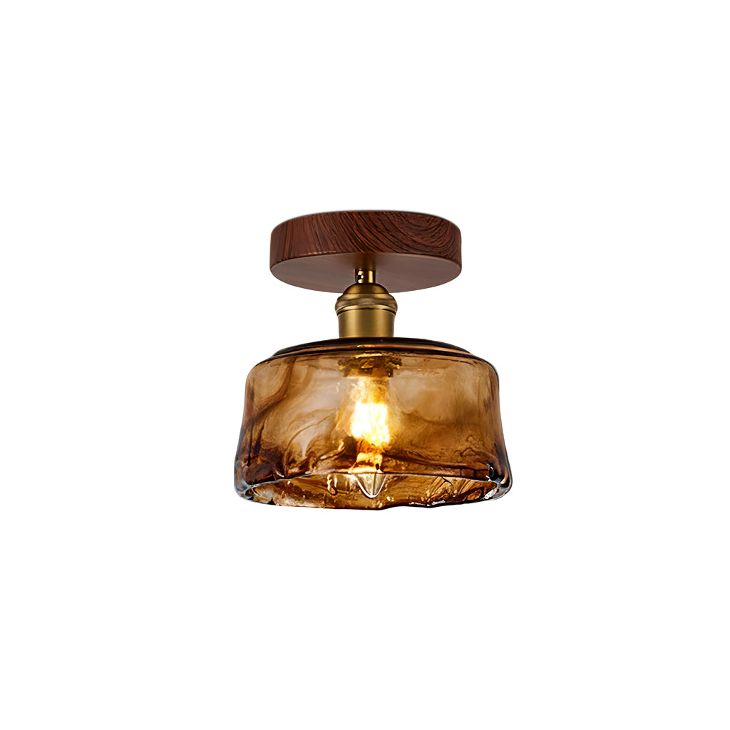 A lit Clérachic flush ceiling light with a wide, flat amber glass shade with a swirled finish, on a round walnut-effect canopy.