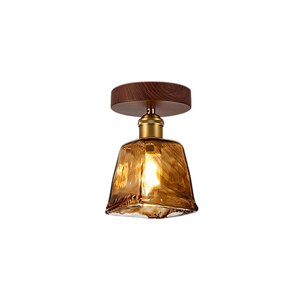 Lit Clérachic flush ceiling light with a squarer amber glass shade with a swirled finish, on a walnut-effect canopy and brass socket.