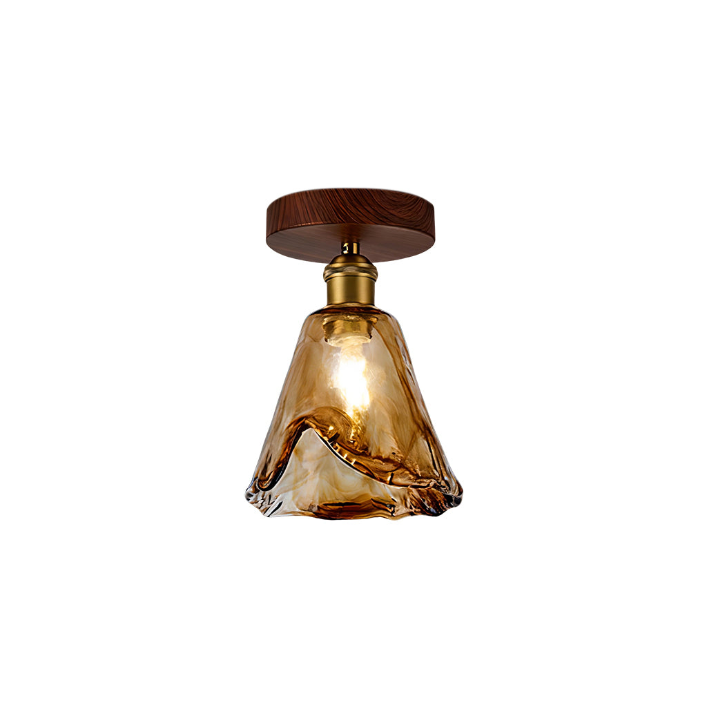 Clérachic flush ceiling light with a tall tapering amber glass shade, lit, with a brass socket and round walnut-effect canopy.