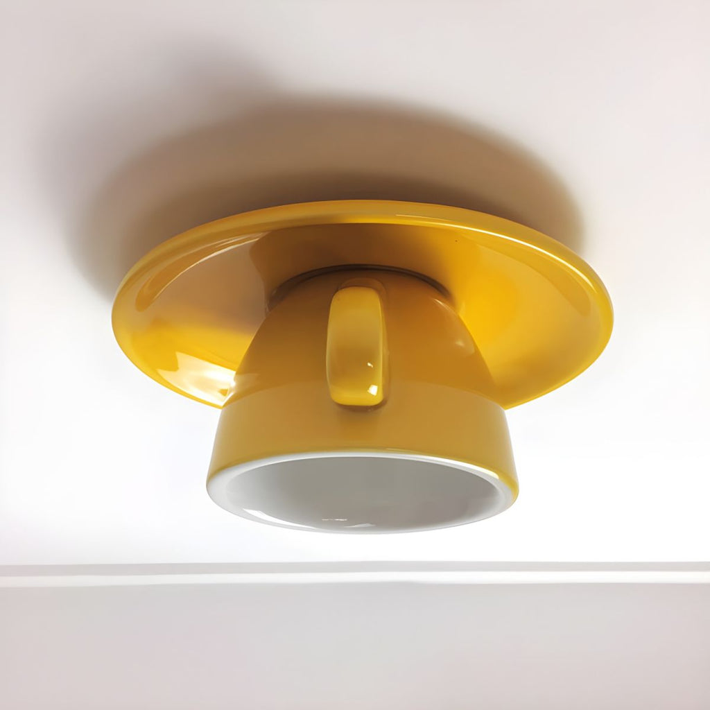 The Clérachic yellow ceramic coffee-cup ceiling light sits flush against a plain white ceiling.