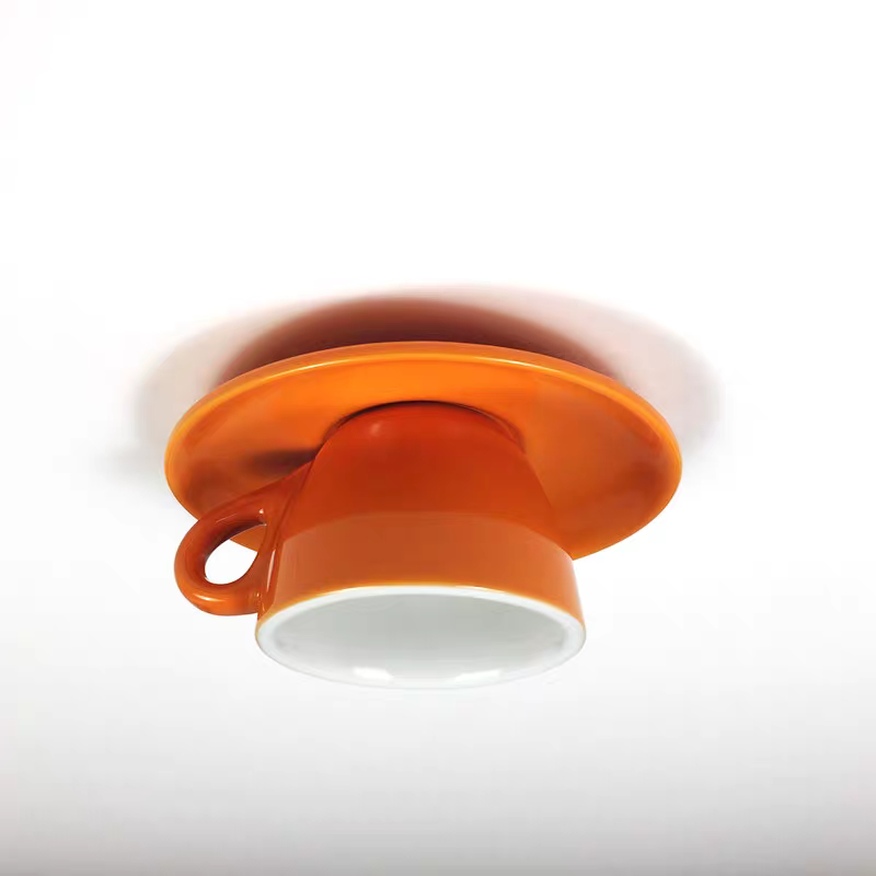 The Clérachic orange coffee-cup flush mount casts a soft shadow on a plain white ceiling.