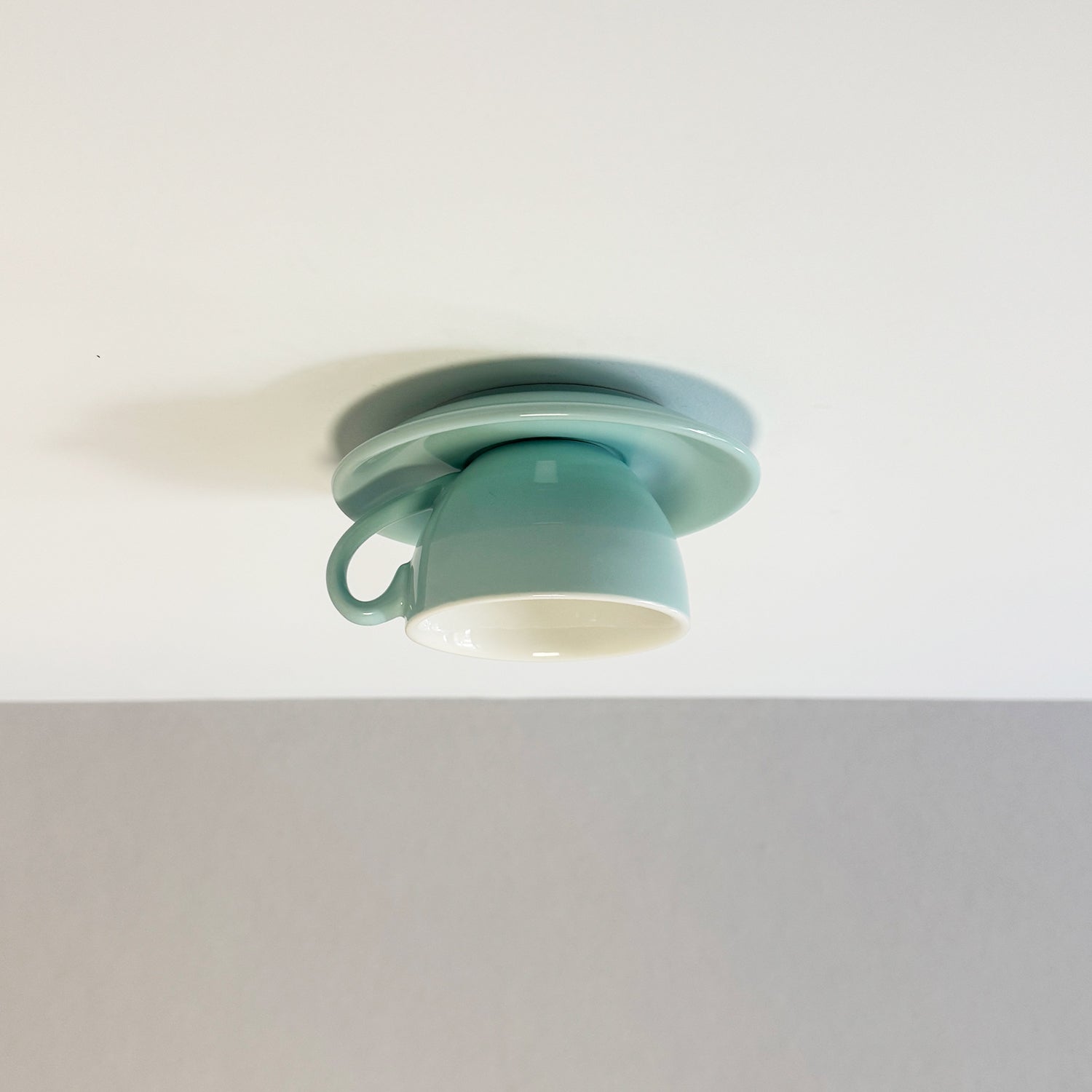Clérachic's light blue coffee-cup flush mount sits against a soft gray ceiling backdrop.