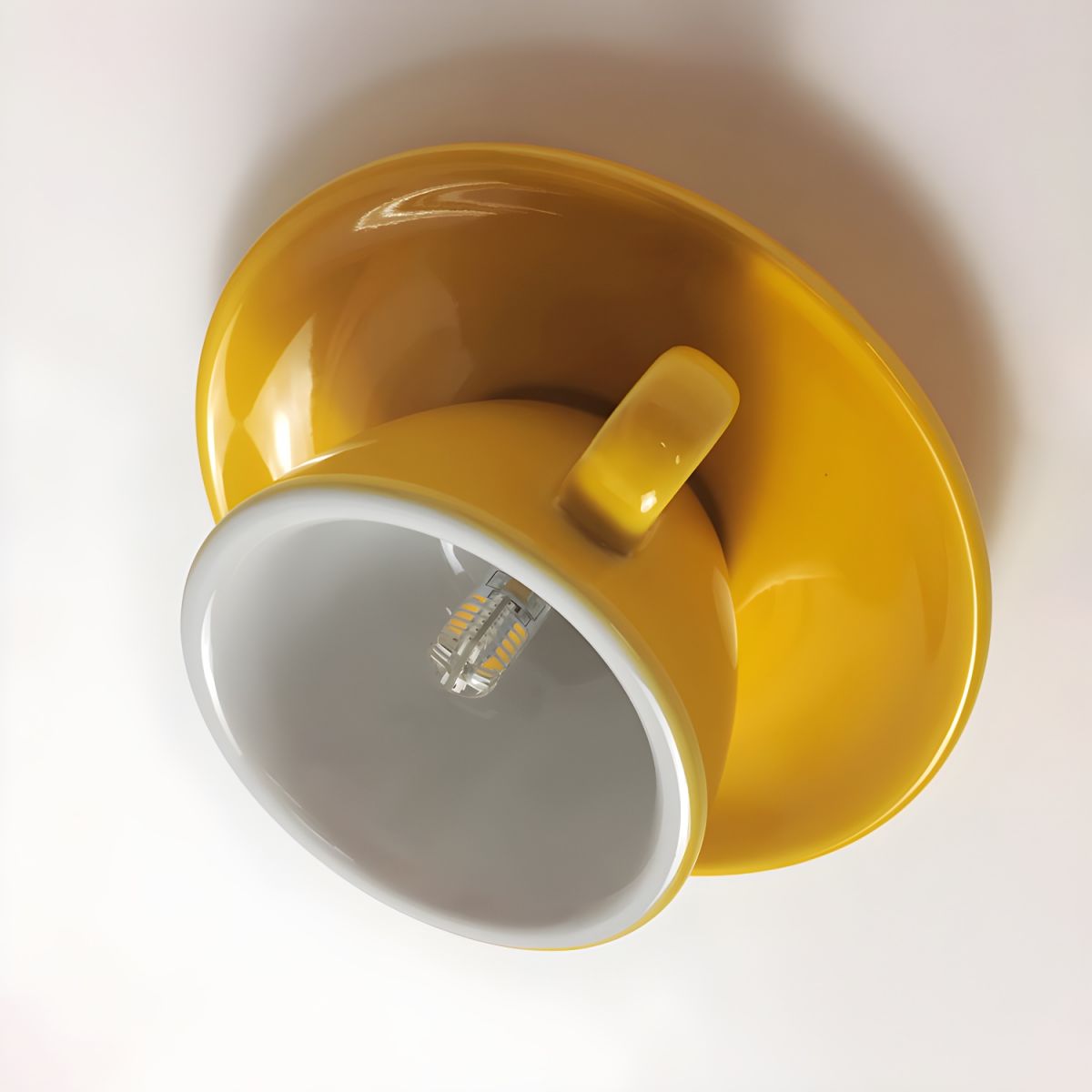 The Clérachic yellow coffee-cup light is shown at an angle, revealing the LED bulb inside.