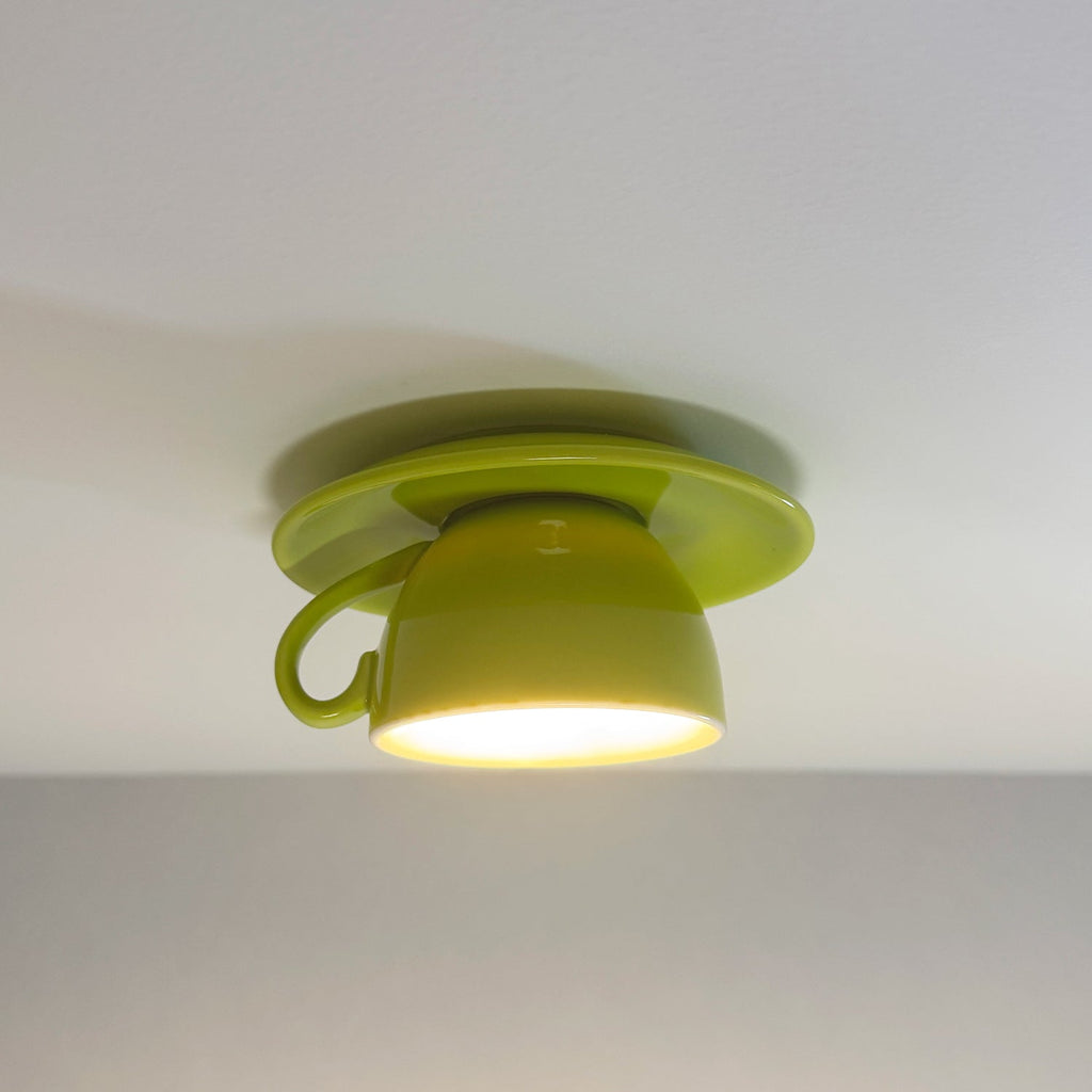 Clérachic's light green coffee-cup ceiling light glows warm against a soft gray backdrop.