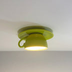 Clérachic's light green coffee-cup ceiling light glows warm against a soft gray backdrop.