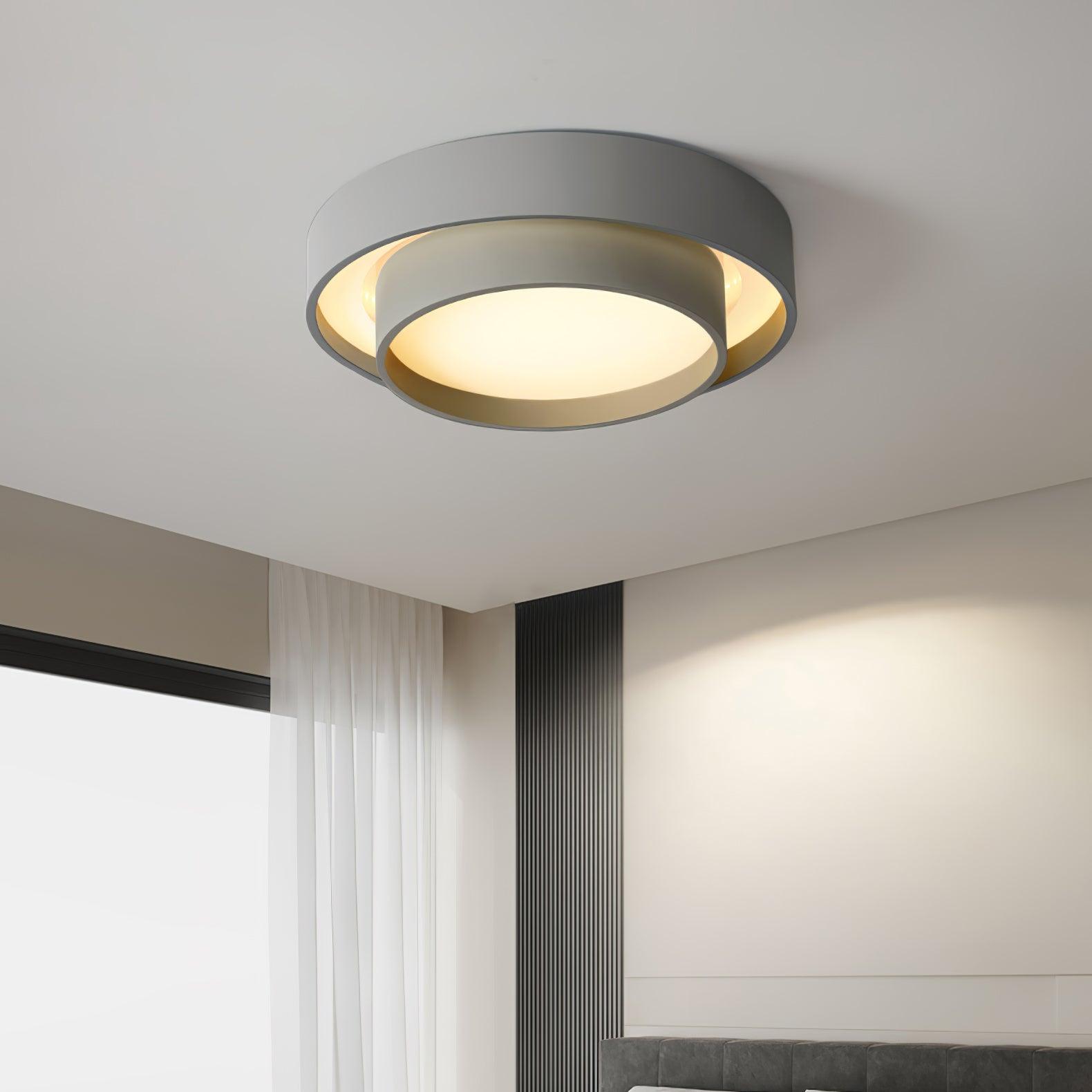 Clérachic's gray double-ring flush mount lights a bedroom corner beside a sheer white curtain.