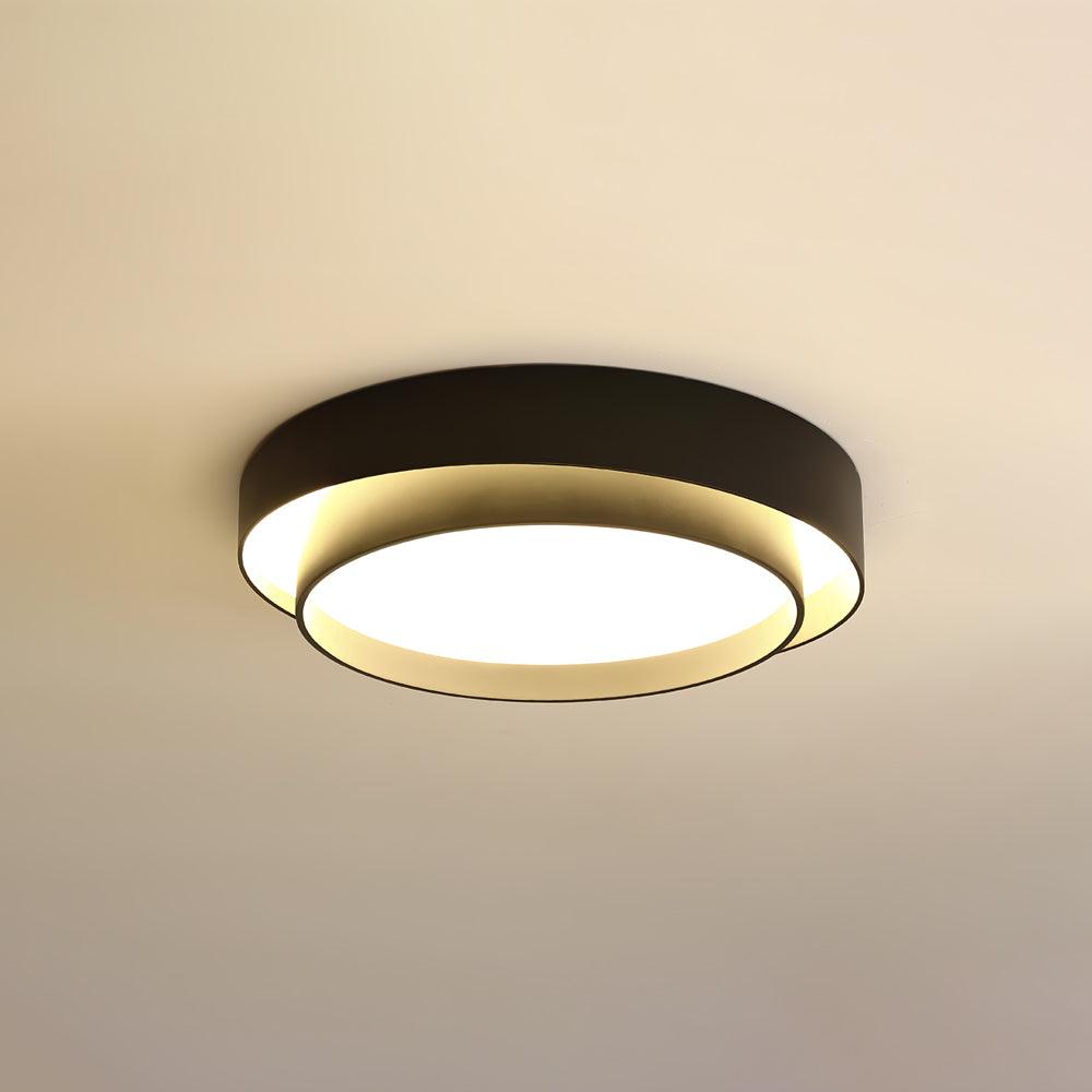 The Clérachic black double-ring ceiling light glows warm against a soft amber-toned ceiling.