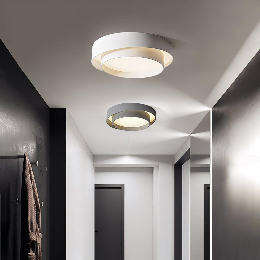 Clérachic's double-ring fixture glows warm on the ceiling, reflected again in a hallway mirror.