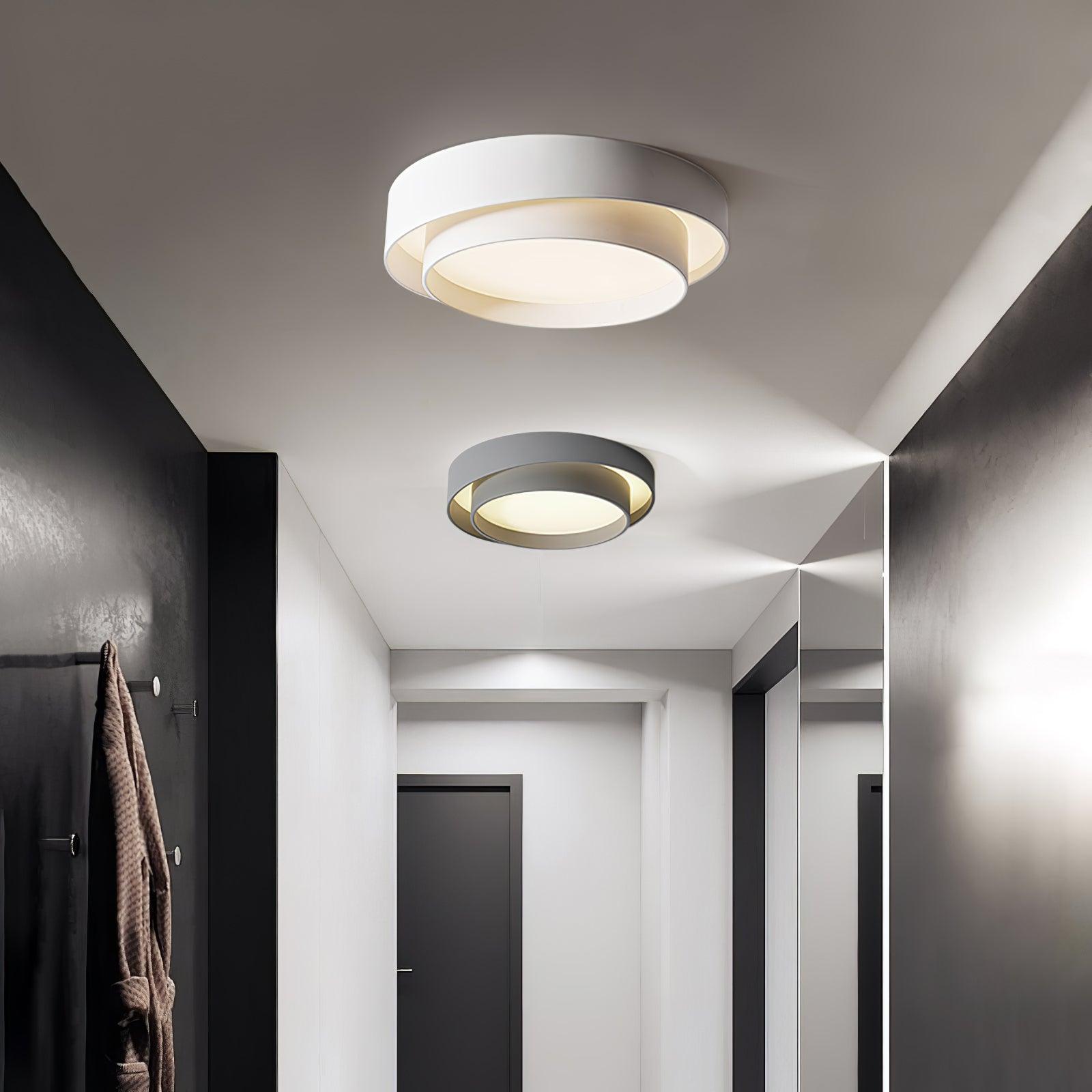 Clérachic's double-ring fixture glows warm on the ceiling, reflected again in a hallway mirror.
