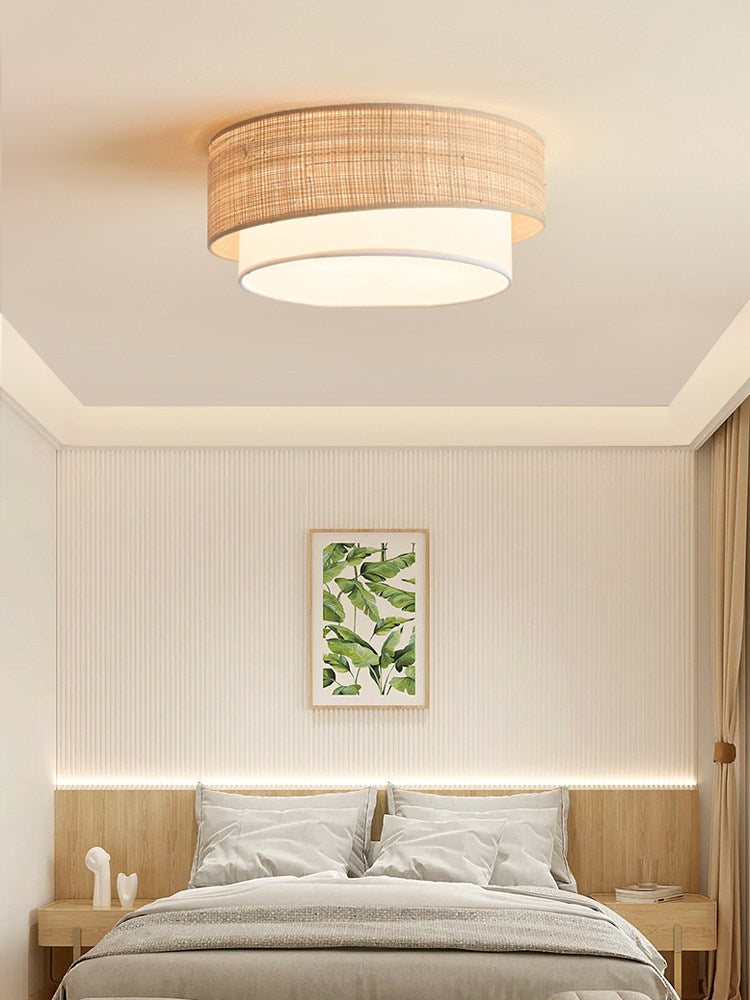 Above a leaf botanical print and grey bedding, this Clérachic ceiling light glows warm in a panelled bedroom.