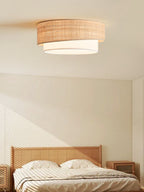 Diagonal window light crosses a bedroom with a rattan headboard beneath this Clérachic flush-mount ceiling light.