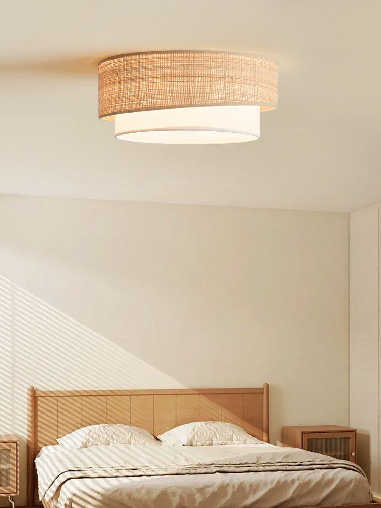Diagonal window light crosses a bedroom with a rattan headboard beneath this Clérachic flush-mount ceiling light.