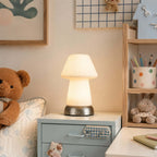On a pale blue chest of drawers in a child's corner, this Clérachic cordless lamp glows beside a teddy bear and a pot of colouring pencils.