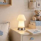 Beside a stack of blue-patterned boxes and a teddy bear, this fluted Clérachic lamp lights a white bedside chest with a picture book.
