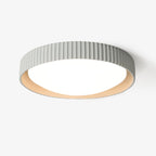 This Clérachic flush ceiling light on a plain white backdrop, a pale grey ribbed shade around a round white diffuser with a cream inner rim.