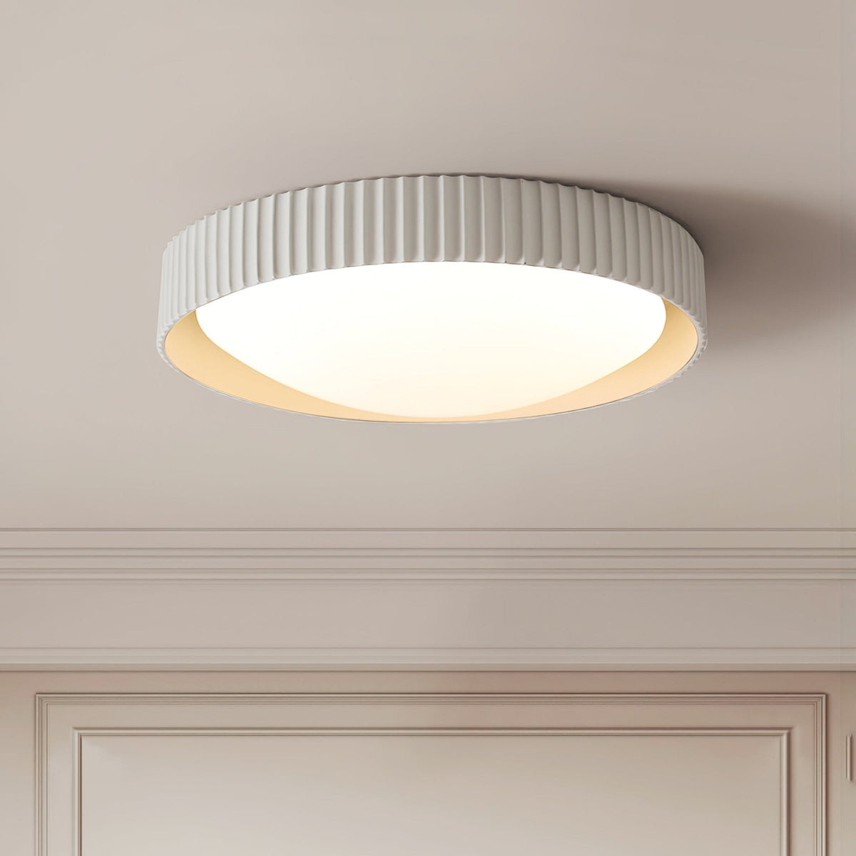 Seen from below on a panelled ceiling, a Clérachic ribbed flush light in pale grey with a glowing white diffuser and a soft cream inner edge.