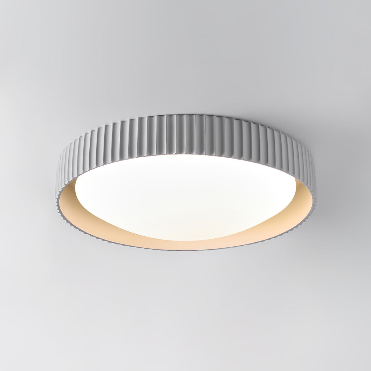 Close view of the fine vertical ribs and round white diffuser on this pale grey Clérachic flush ceiling light, against a grey wall.