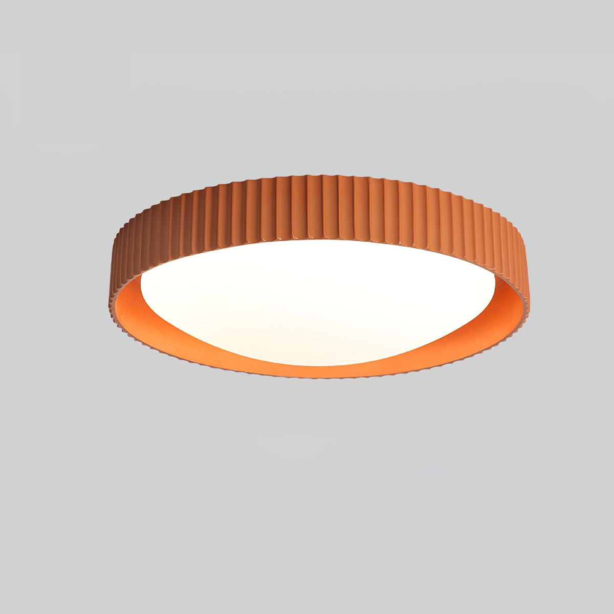 Angled view of the orange ribbed rim and bright inner edge of this Clérachic flush ceiling light, on a grey backdrop.
