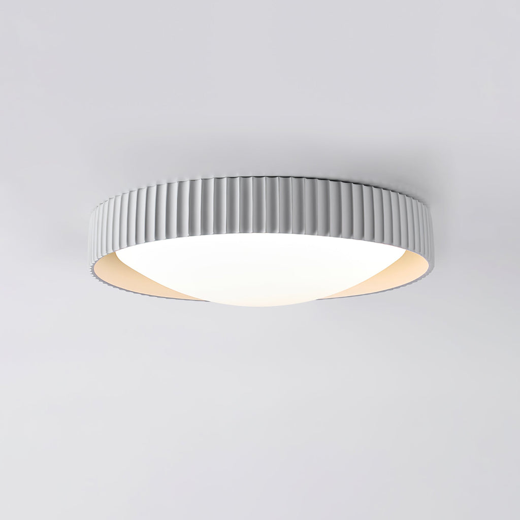 A pale grey Clérachic flush ceiling light seen from below, its ribbed drum rim sitting low and flat to a light grey ceiling.