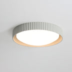 Pale grey Clérachic ribbed flush ceiling light from below, its slim rim and lit white diffuser glowing on a light grey ceiling.