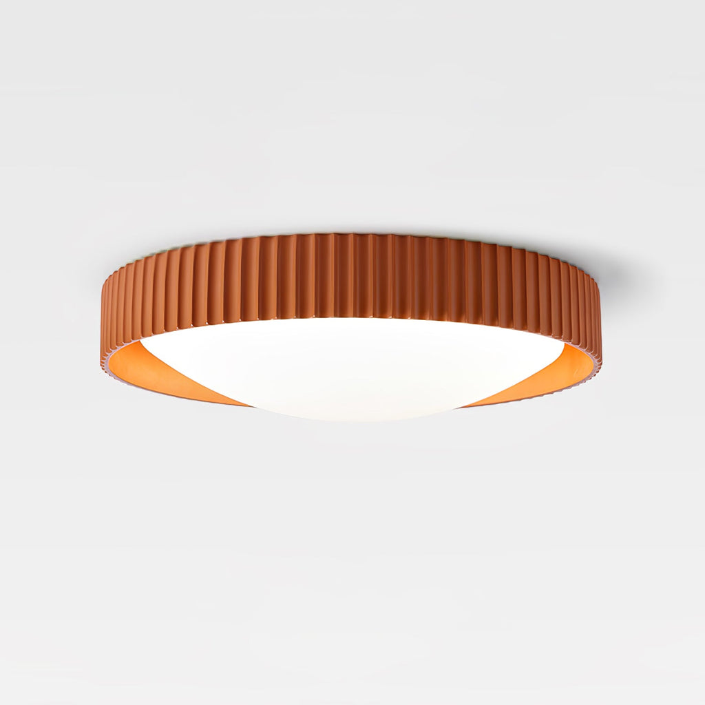 An orange Clérachic ribbed flush ceiling light on a plain white ceiling, shown from the side with its low profile and lit diffuser.