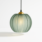 Clérachic ribbed opaline glass pendant light in sage green, brass canopy, glowing warm against a plain white backdrop.