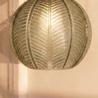 Clérachic ribbed opaline glass shade in sage green, a macro crop of the leaf-vein texture glowing warm from within.