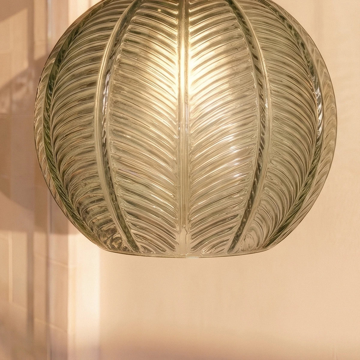 Clérachic ribbed opaline glass shade in sage green, a macro crop of the leaf-vein texture glowing warm from within.