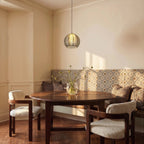 Clérachic ribbed opaline glass pendant light in sage green hung low over a round wood dining table at golden hour.