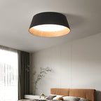Black Clérachic ceiling light with a wood-grain interior over a bedroom with a tan headboard, a tall window and grey curtains.