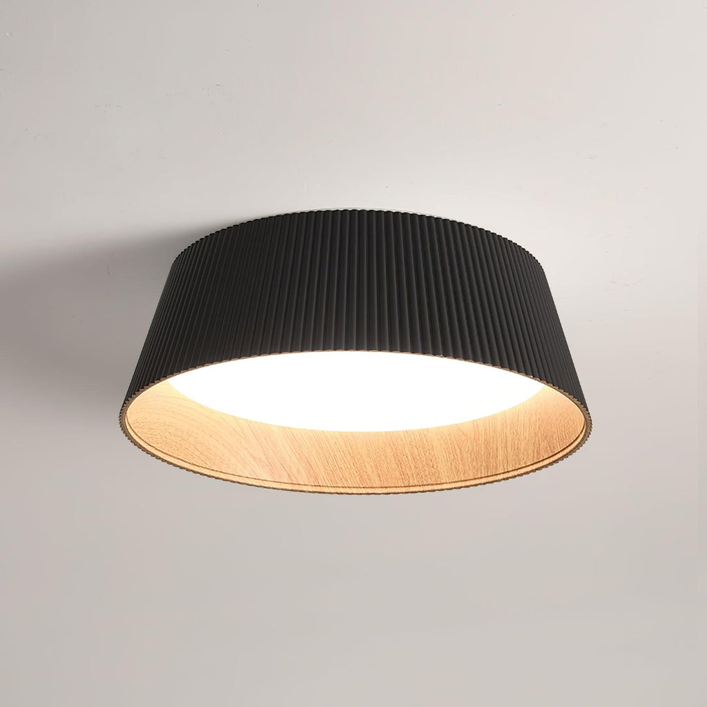 Black fluted Clérachic ceiling light with a wood-grain inner rim, seen from below against a soft grey ceiling.