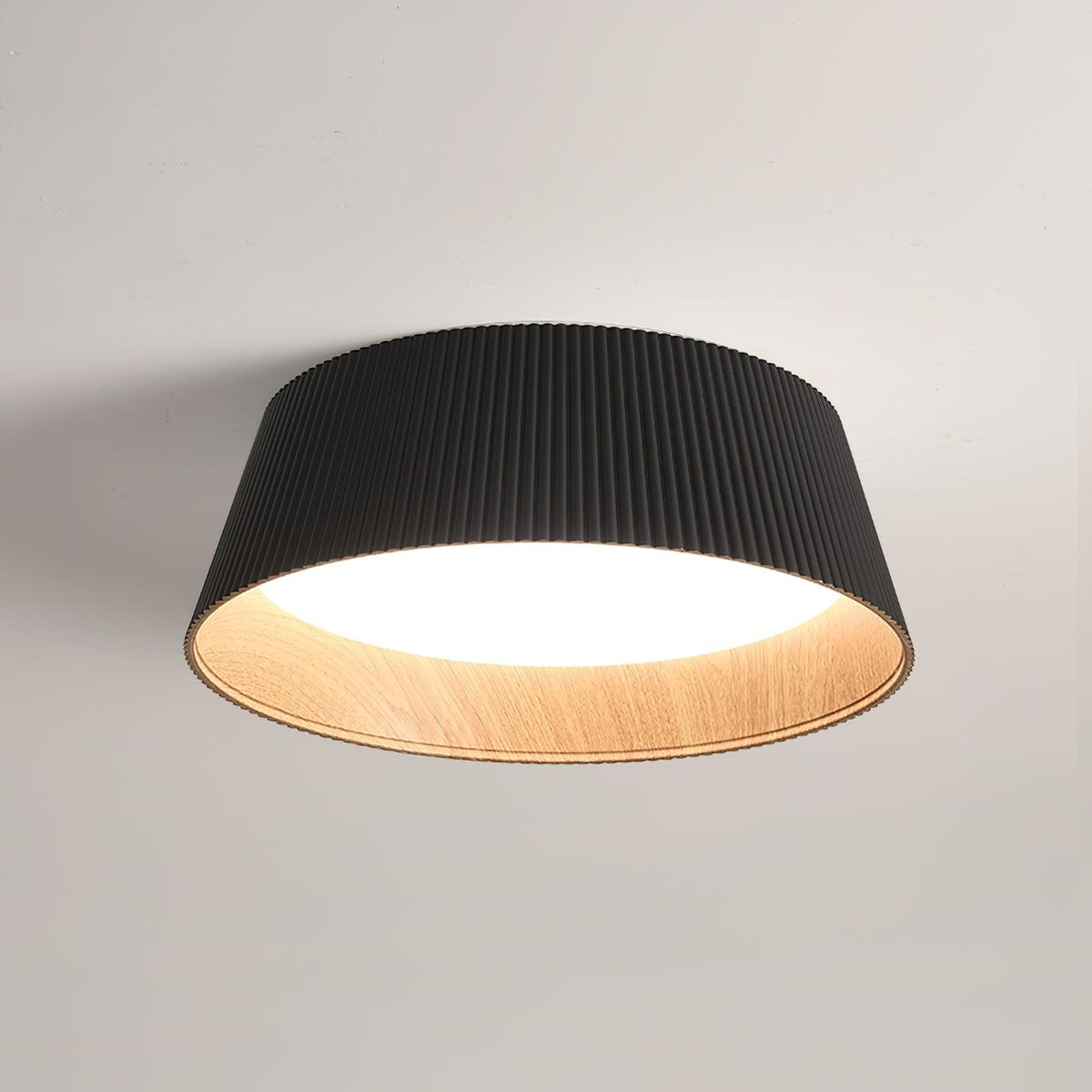 Black fluted Clérachic ceiling light with a wood-grain inner rim, seen from below against a soft grey ceiling.