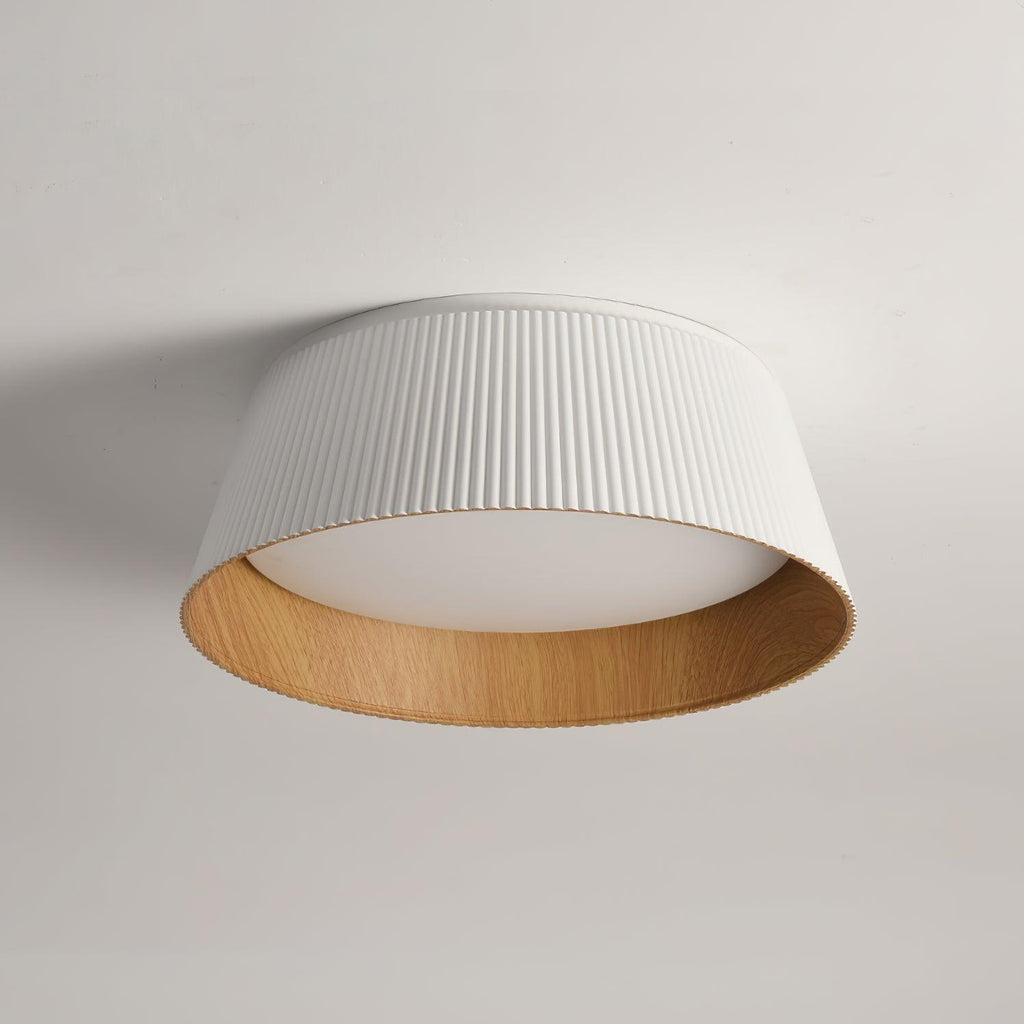 A white fluted Clérachic ceiling light with a wood-grain inner rim and a frosted diffuser, on a pale grey ceiling.