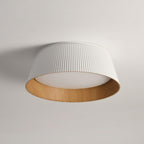 A white fluted Clérachic ceiling light with a wood-grain inner rim and a frosted diffuser, on a pale grey ceiling.