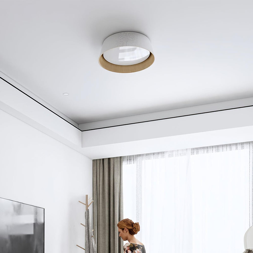 Small white Clérachic ceiling light on a ceiling with a recessed edge, above a room with sheer curtains and a woman at the edge.