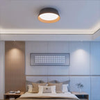 Black Clérachic ceiling light above a bedroom with a slatted wood panel, a grey padded headboard and a framed grid artwork.