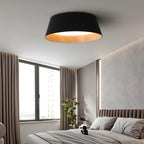 A black Clérachic ceiling light in a bedroom with a tall window, brown curtains and a ribbed headboard on a taupe wall.